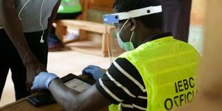An Independent Election and Boundaries Commission (IEBC) official adorning a face shield and hand gloves uses the Kems kit