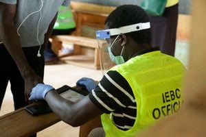 An Independent Election and Boundaries Commission (IEBC) official adorning a face shield and hand gloves uses the Kems kit